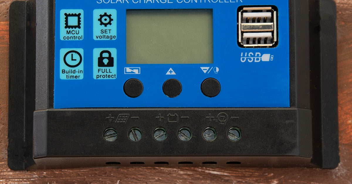 A small blue solar charge controller is installed on a brick wall. The screen is blank, and nothing is connected to it.