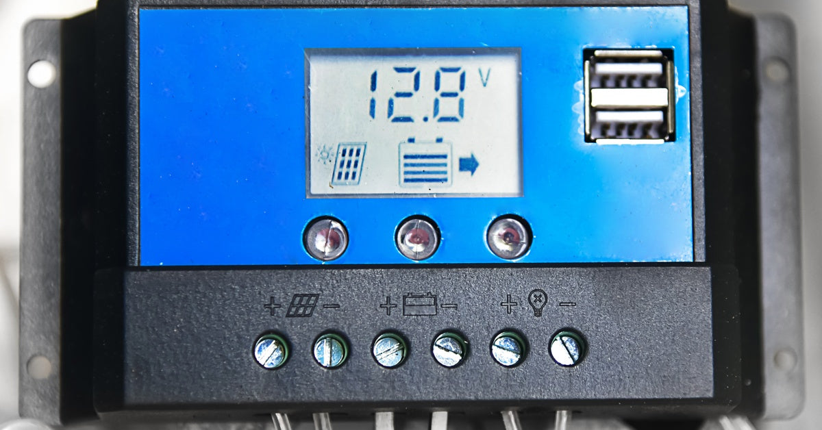 A close-up of a blue solar panel charge controller with a digital display. The display screen reads 12.8 volts.