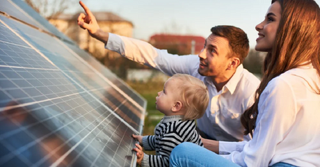 Family with a man, woman, and baby looking at solar panels