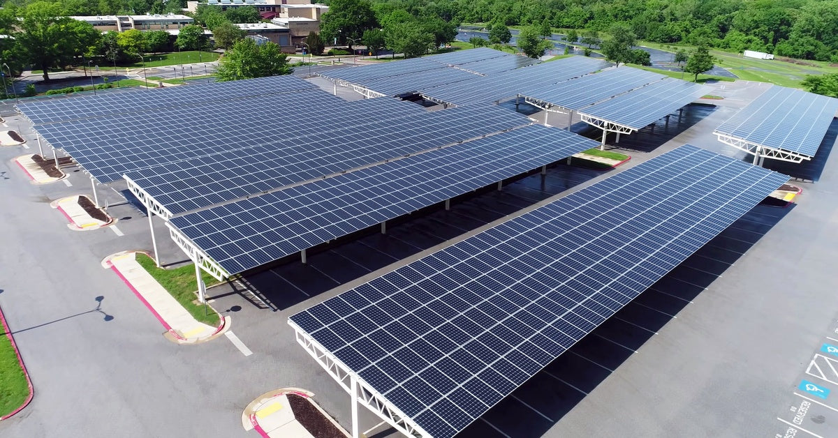 Multiple large solar panels installed in a parking lot in such a way that cars can park in the shade beneath them.
